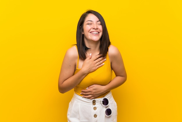 Joven mexicana sobre amarillo aislado sonriendo mucho