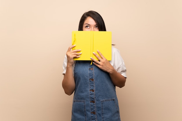 Joven mexicana sobre tenencia aislada y leyendo un libro