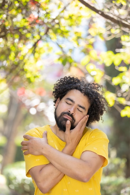 Joven mexicano con barba y afro abrazándose a sí mismo concepto de amor propio