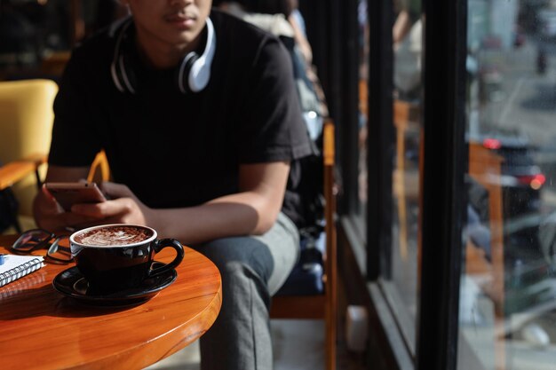 Joven milenario se aburre esperando a su amigo en la cafetería.