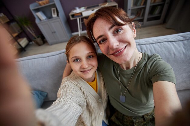 Joven militar tomando una foto selfie con su hija en casa