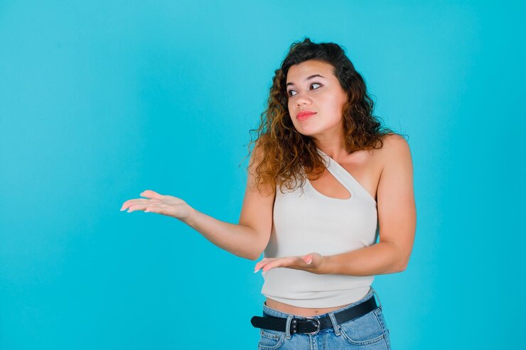 Foto la joven mira a la derecha apuntando a la derecha con las manos en el fondo azul