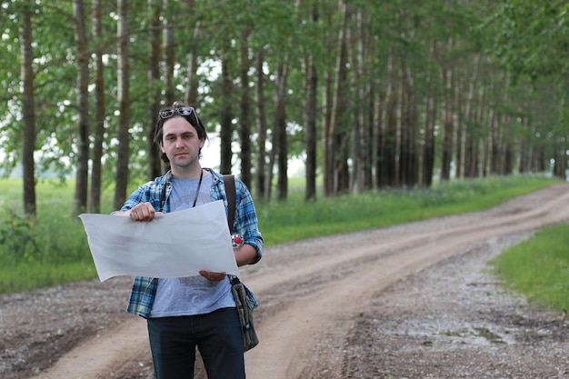 Un joven mira un mapa en la naturaleza para no perdersexA