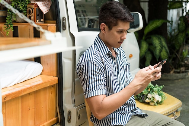Joven mirando a la cámara mientras está de pie en el teléfono móvil