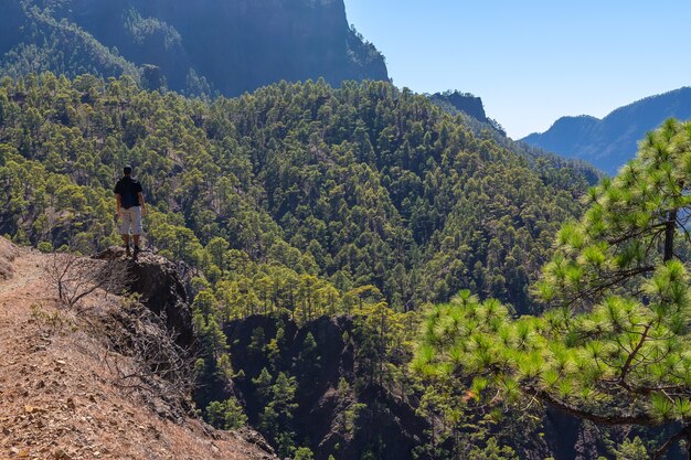 Un joven mirando el paisaje en la caminata desde la cima de La Cumbrecita junto a las montañas de la Caldera de Taburiente, isla de La Palma, Islas Canarias, España