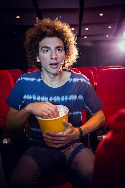 Joven mirando una película y comiendo palomitas de maíz