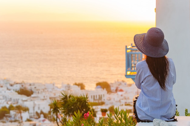 Foto joven está mirando la puesta de sol sobre un mar en el famoso pueblo de mykonos