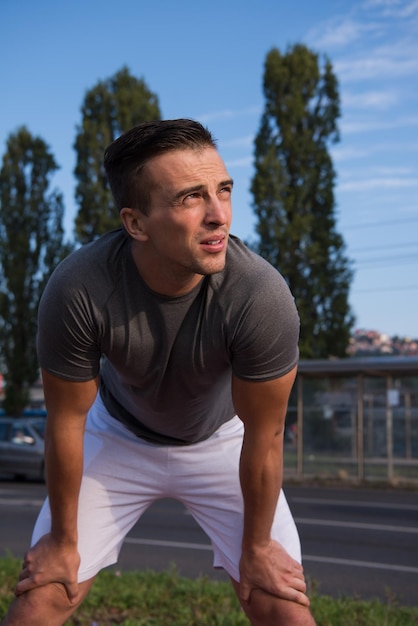 Foto joven mirando el resto del camino durante un descanso de su entrenamiento para trotar al aire libre