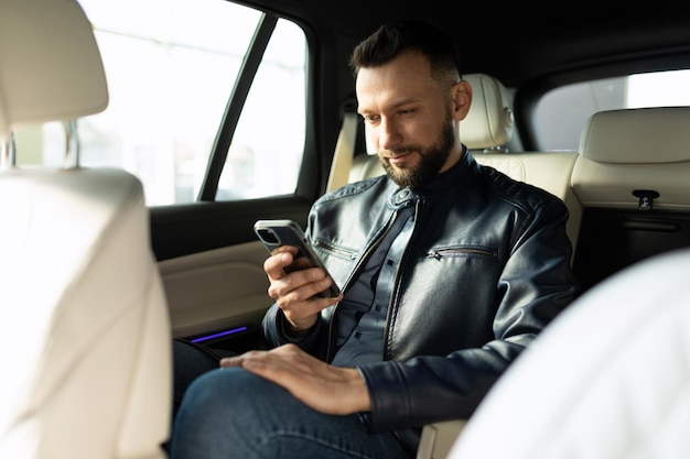 Joven mirando el teléfono en el asiento trasero del auto