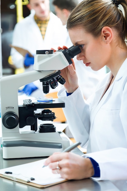 Joven mirando a través de microscopio en el laboratorio.