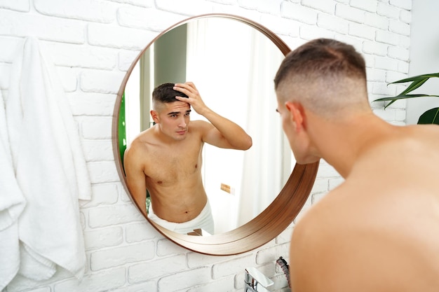 Joven mirándose en el espejo en el baño preparándose para el día