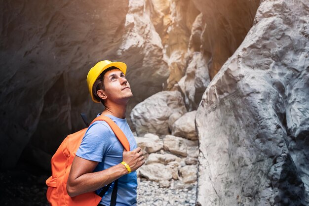 Foto joven con mochila y casco caminando a través de un cañón profundo y pintoresco recreación extrema y activa