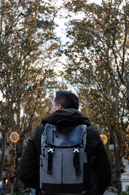 joven con una mochila gris mirando los árboles