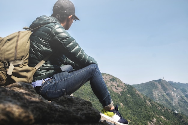 Joven mochilero disfrutando de una vista del valle desde la cima de una montaña.