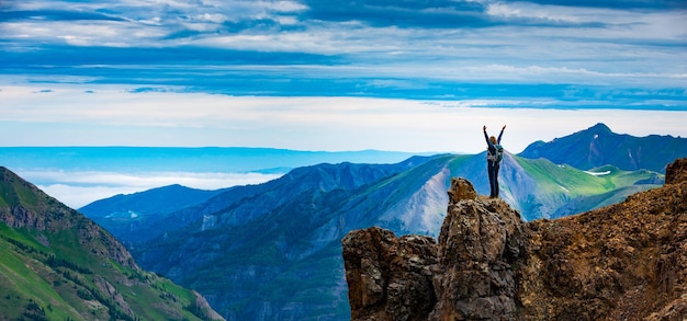 Joven mochilero en pose de victoria con los brazos levantados en la cima de la montaña Colorado, EE.UU.