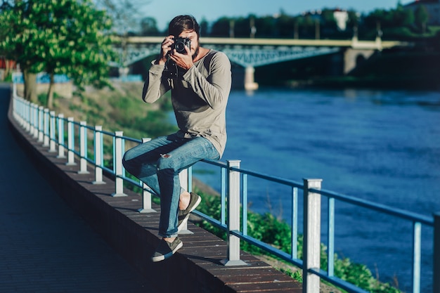 Joven de moda toma una foto con una vieja cámara retro en el parque