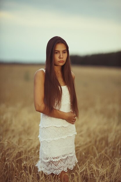 Joven modelo glamorosa posando en un campo de trigo