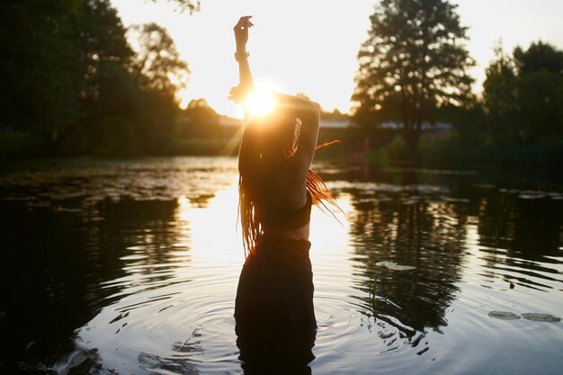 La joven modelo posa en el lago por la noche antes del atardecer