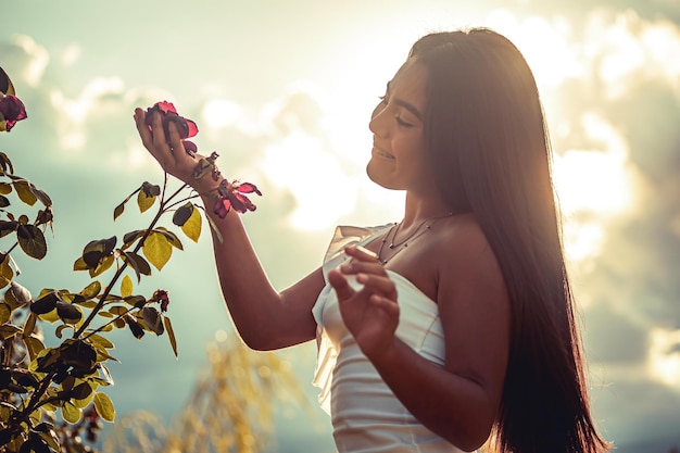 Joven modelo sosteniendo una flor al atardecer