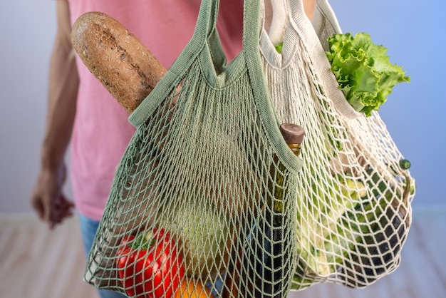 Joven moderno sosteniendo una cadena de bolsas con compras