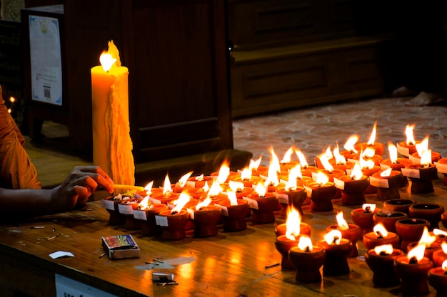 El joven monje tailandés enciende una vela de fuego por respeto orando el ángel de la deidad del dios buda con el culto sagrado del misterio del mito de la bendición en el monasterio de la pagoda del templo Wat Prasat el 8 de noviembre de 2022 en Nonthaburi Tailandia