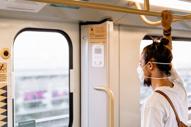 Un joven con un moño lleva una máscara en el metro