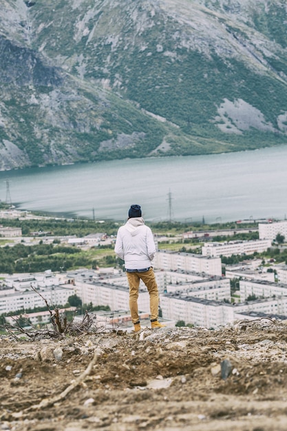 Un joven se para en una montaña y contempla un hermoso paisaje.