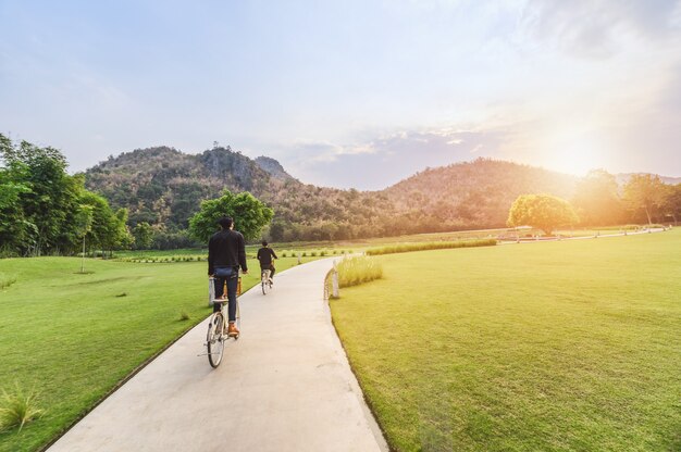 Joven montando bicicleta retro en parque público con luz solar