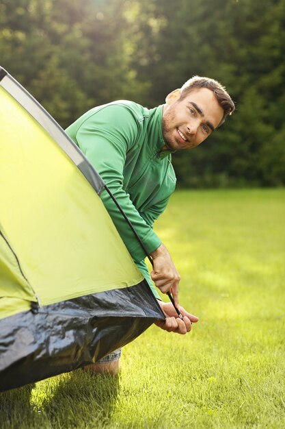 joven montando carpa en el bosque