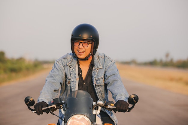 Joven montando una gran moto en bicicleta de asfalto camino alto contra, el hombre de la moto tiene libertad