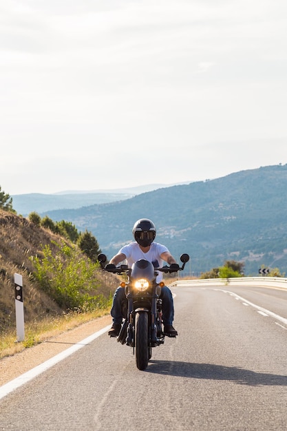 Un joven montando una motocicleta en la carretera contra un cielo despejado