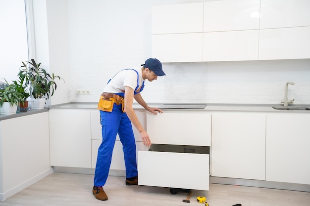 Joven montando muebles de cocina.