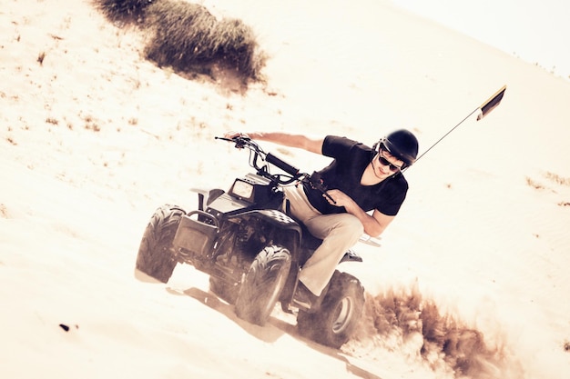 Un joven montando en quad en el desierto en un día soleado