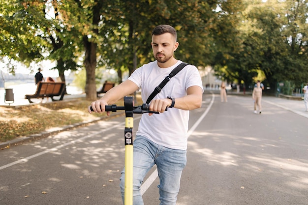 Joven montando un scooter eléctrico en una reunión concepto de transporte ecológico guapo