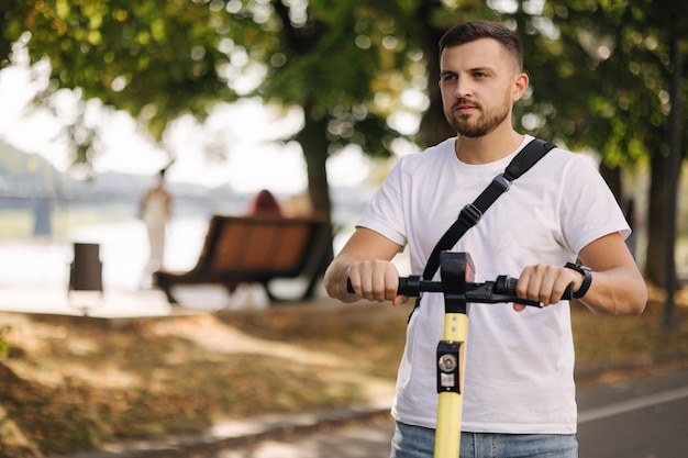 Joven montando un scooter eléctrico en una reunión concepto de transporte ecológico guapo