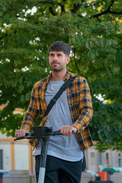 Joven montando un scooter eléctrico a través de un parque