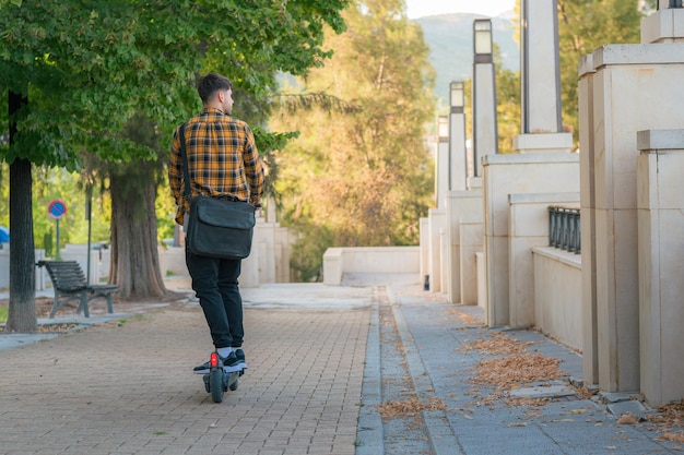 Joven montando un scooter eléctrico a través de un parque