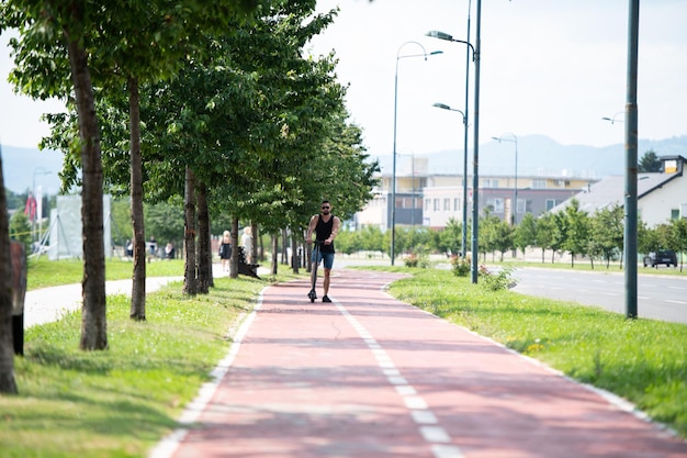 Joven montando un scooter eléctrico en verano en la calle