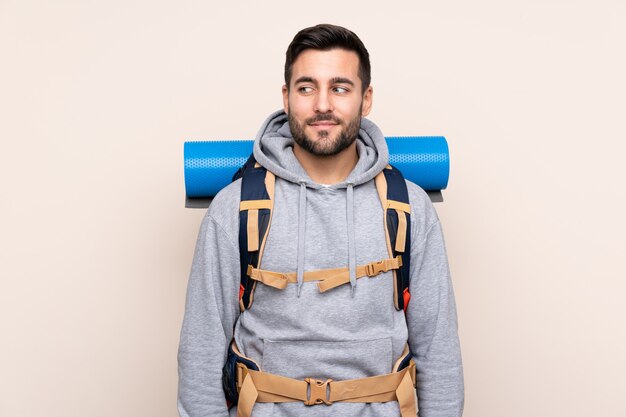 Joven montañero con una gran mochila de pie y mirando hacia un lado