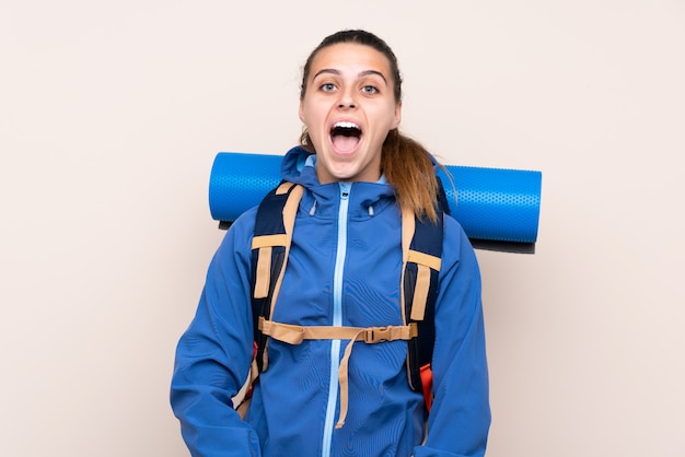 Joven montañero con una mochila grande con expresión facial sorpresa