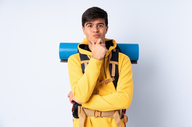 Joven montañero con una mochila grande sobre risa azul aislado