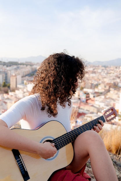 Joven morena aprende a tocar la guitarra clásica al aire libre