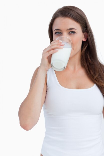 Joven morena bebiendo un vaso de leche