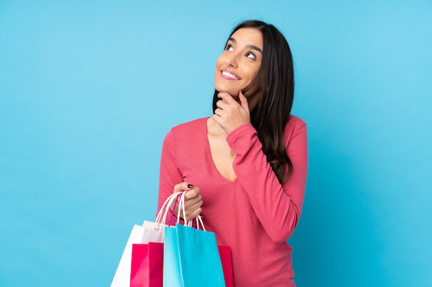 Joven morena con bolsas de compras y pensamiento