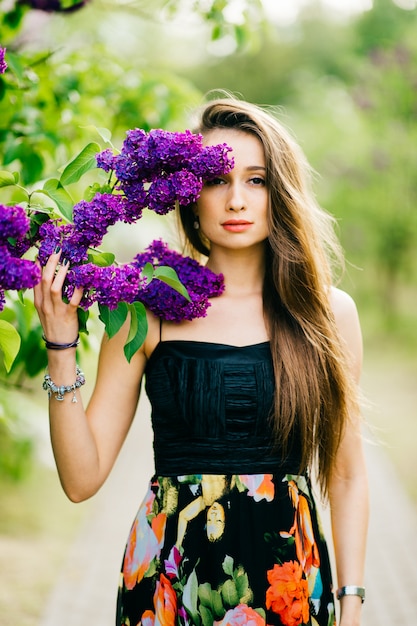 Joven morena con brunch de flores lilas en el parque