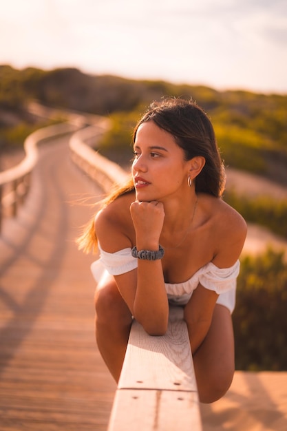 Una joven morena caucásica disfrutando de las vacaciones en la playa con un vestido blanco en verano