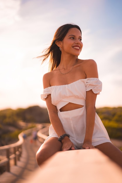 Una joven morena caucásica de vacaciones en la playa con un vestido blanco en verano