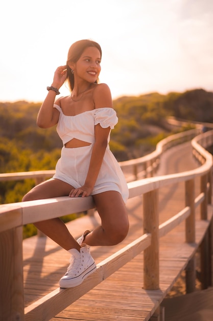 Una joven morena caucásica de vacaciones en la playa con un vestido blanco en verano