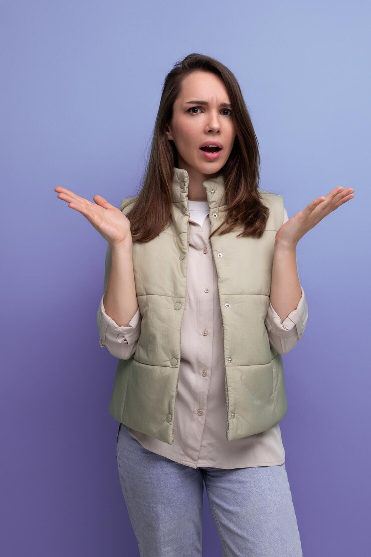 Foto una joven morena concentrada y molesta con chaleco y camisa en el estudio.