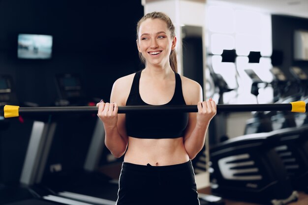 Joven morena deportiva ejercicio con mancuernas en un gimnasio